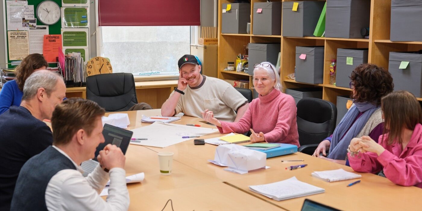 A group of learners sit around a table and discuss their lecture