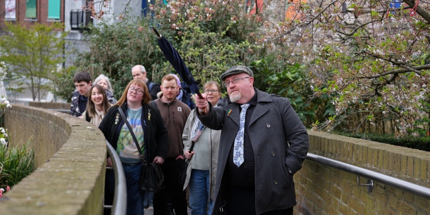 A tour guide uses an umbrella to indicate a point of interest to the tour attendees