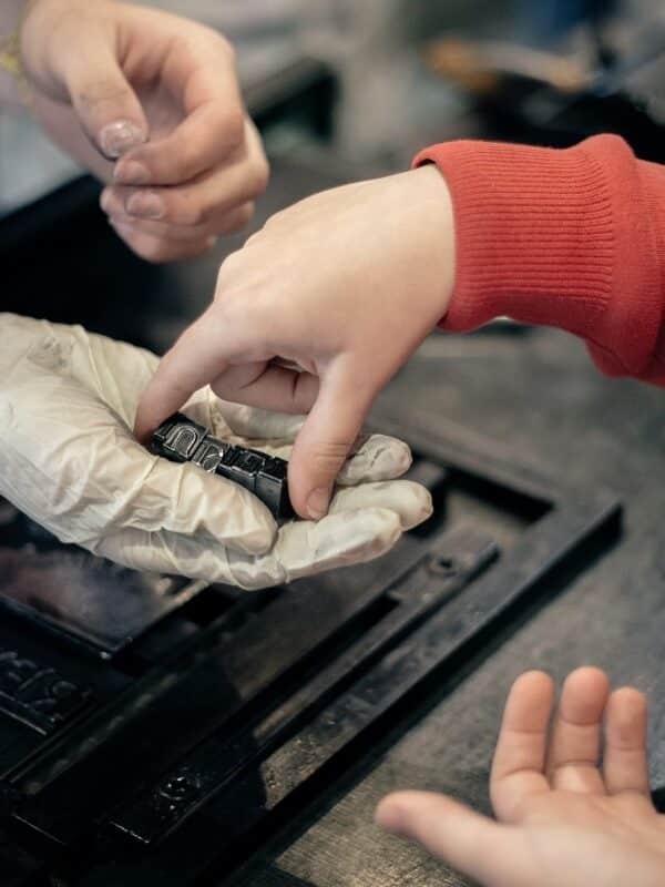 A student hands their composed name in type to a tour guide