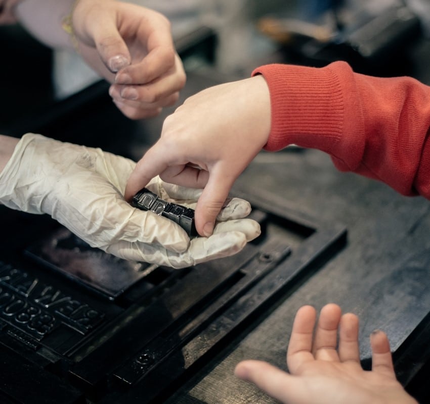 A student hands their composed name in type to a tour guide