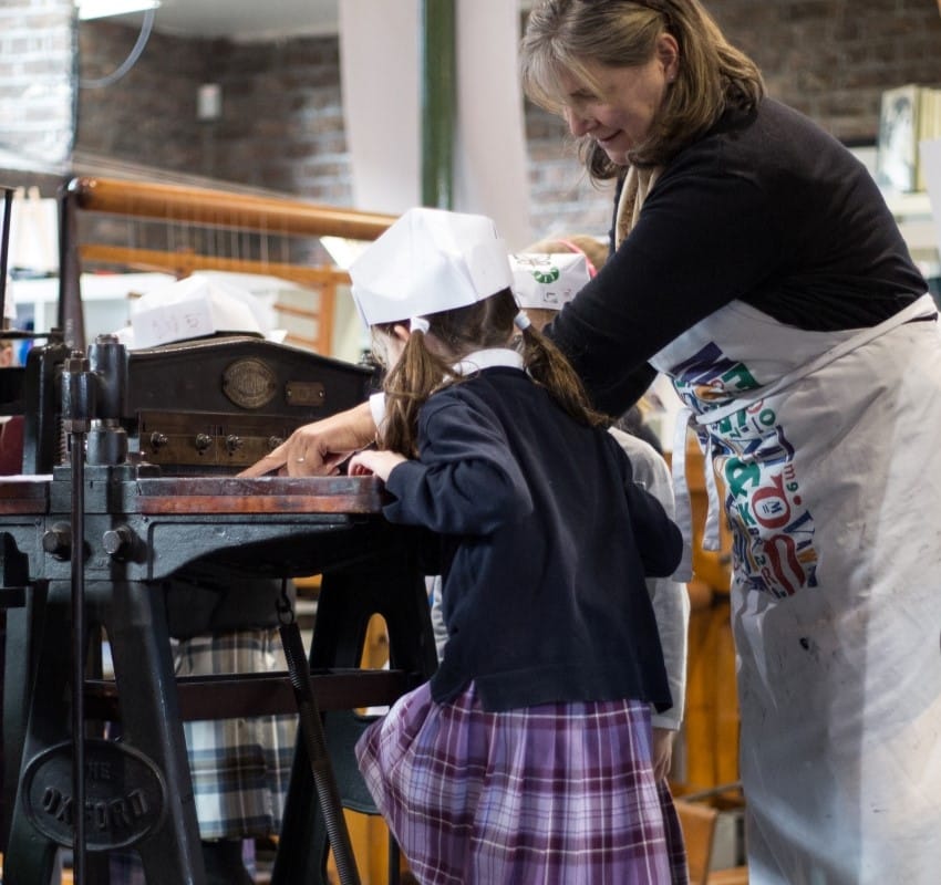 A tour guide assists a student with operating the perforator