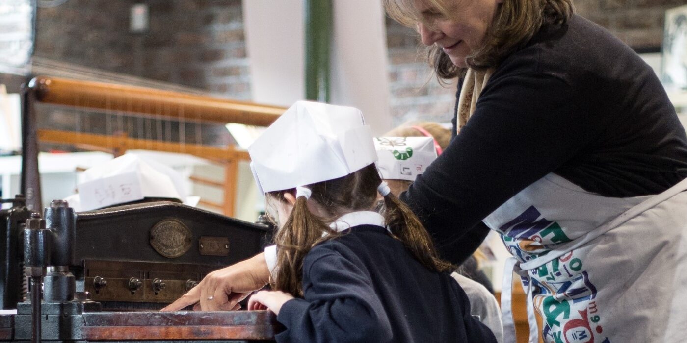A tour guide assists a student with operating the perforator