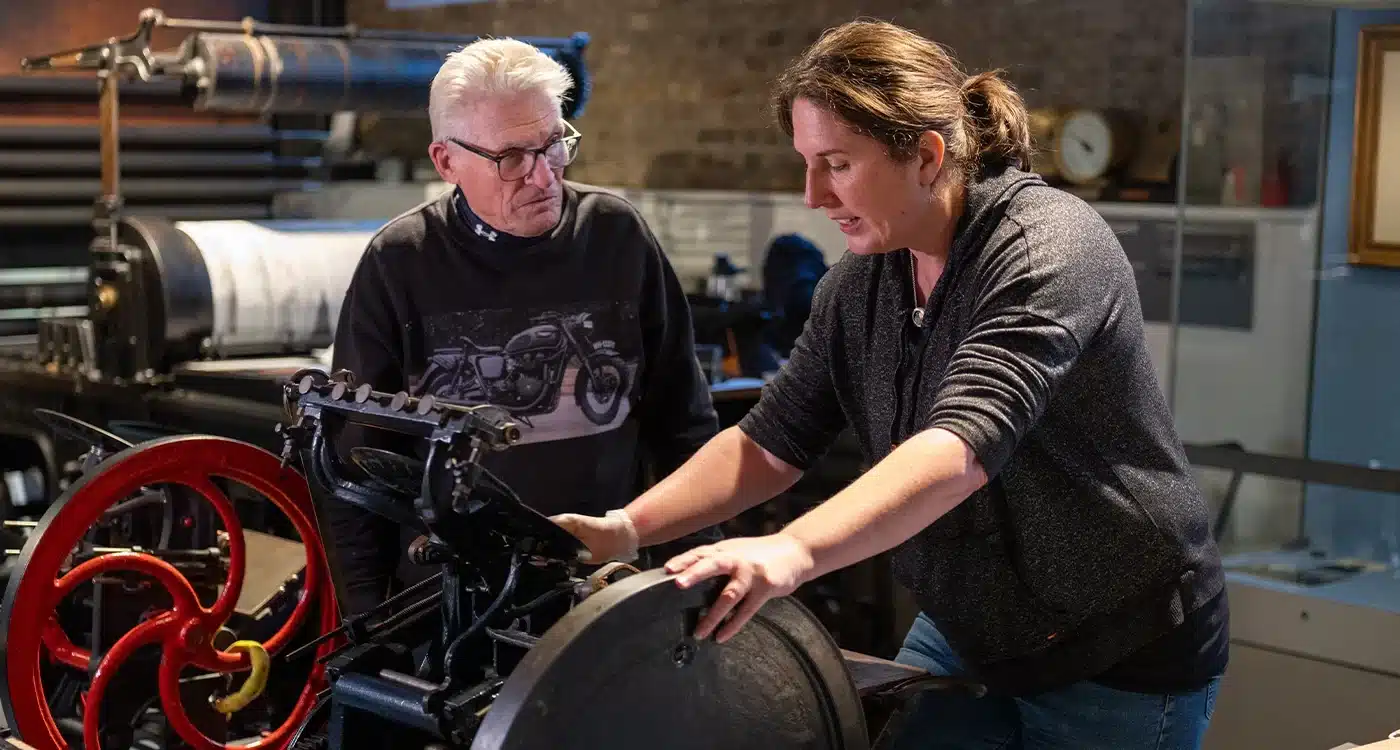 Woman working at printer while person observes