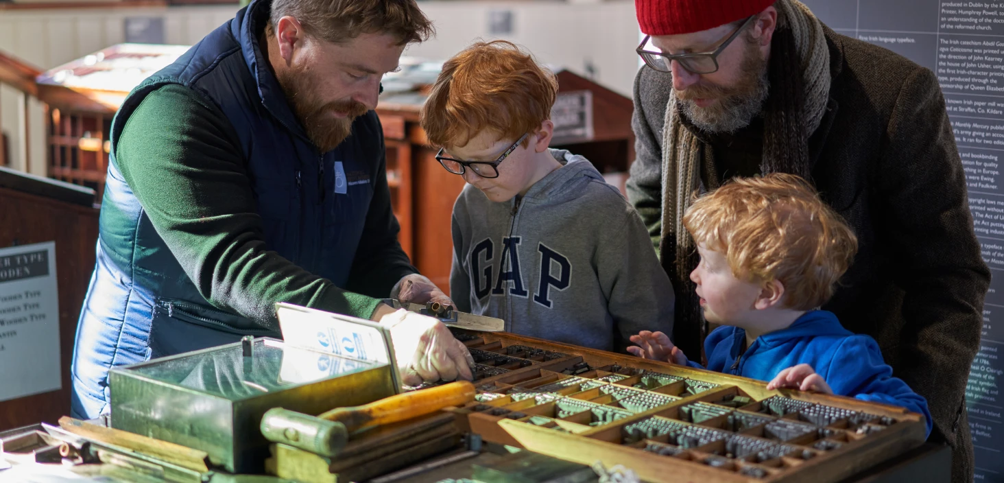 father children looking at print machine