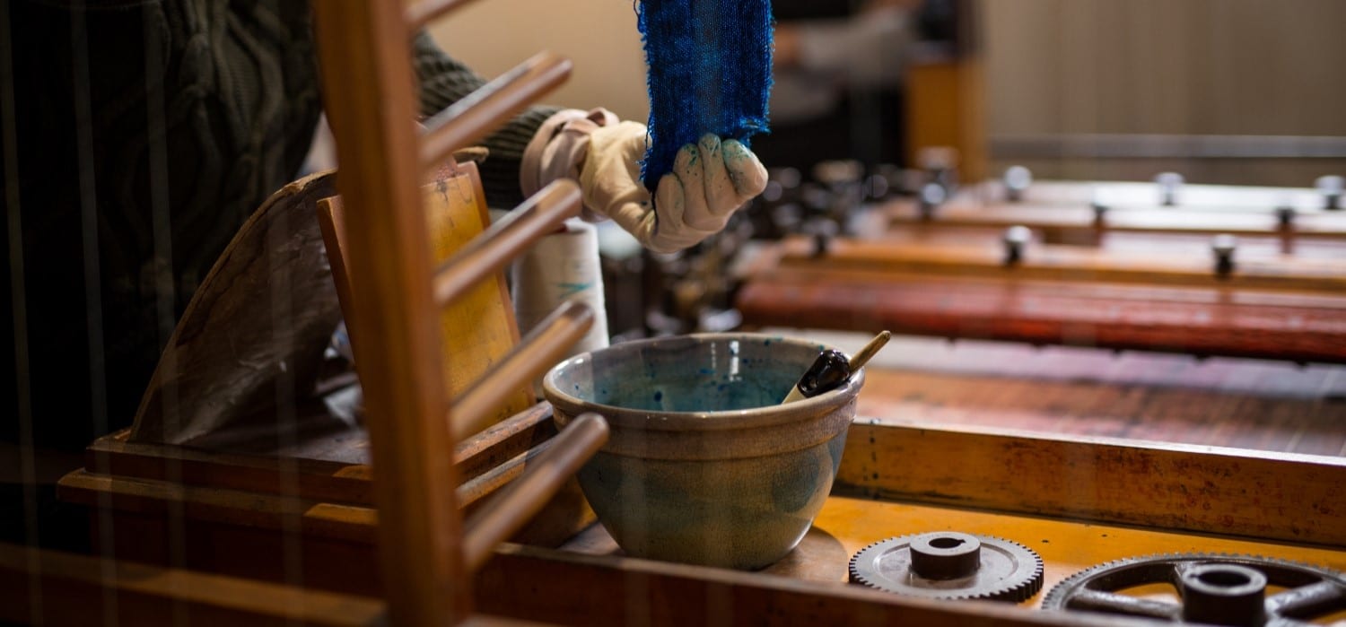 An operator wets the cloth in ink in preparation for using the Shaw Pen Ruling Machine