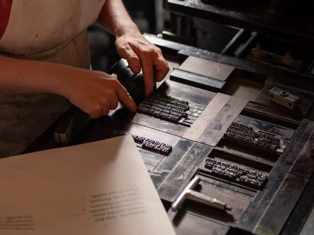 A compositor adjusting type inside a forme to prepare it for printing