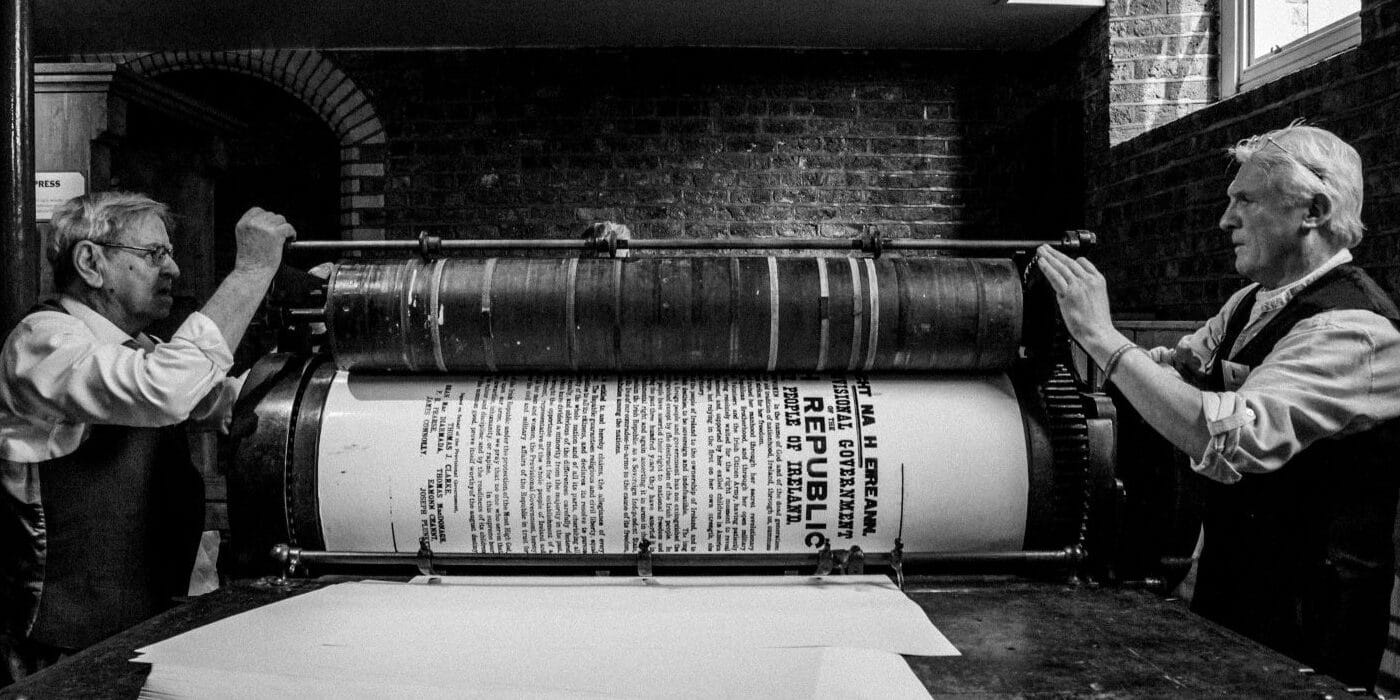 Two retired printers printing a replica Proclamation on a Wharfdale stop-cylinder press