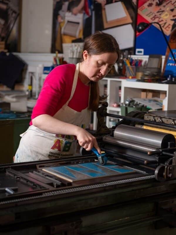 A printer inking a forme on a Vandercook proofing press