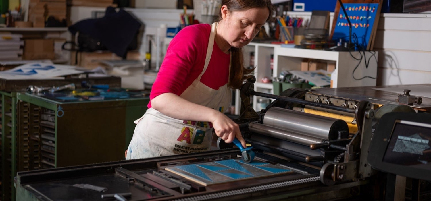A printer inking a forme on a Vandercook proofing press