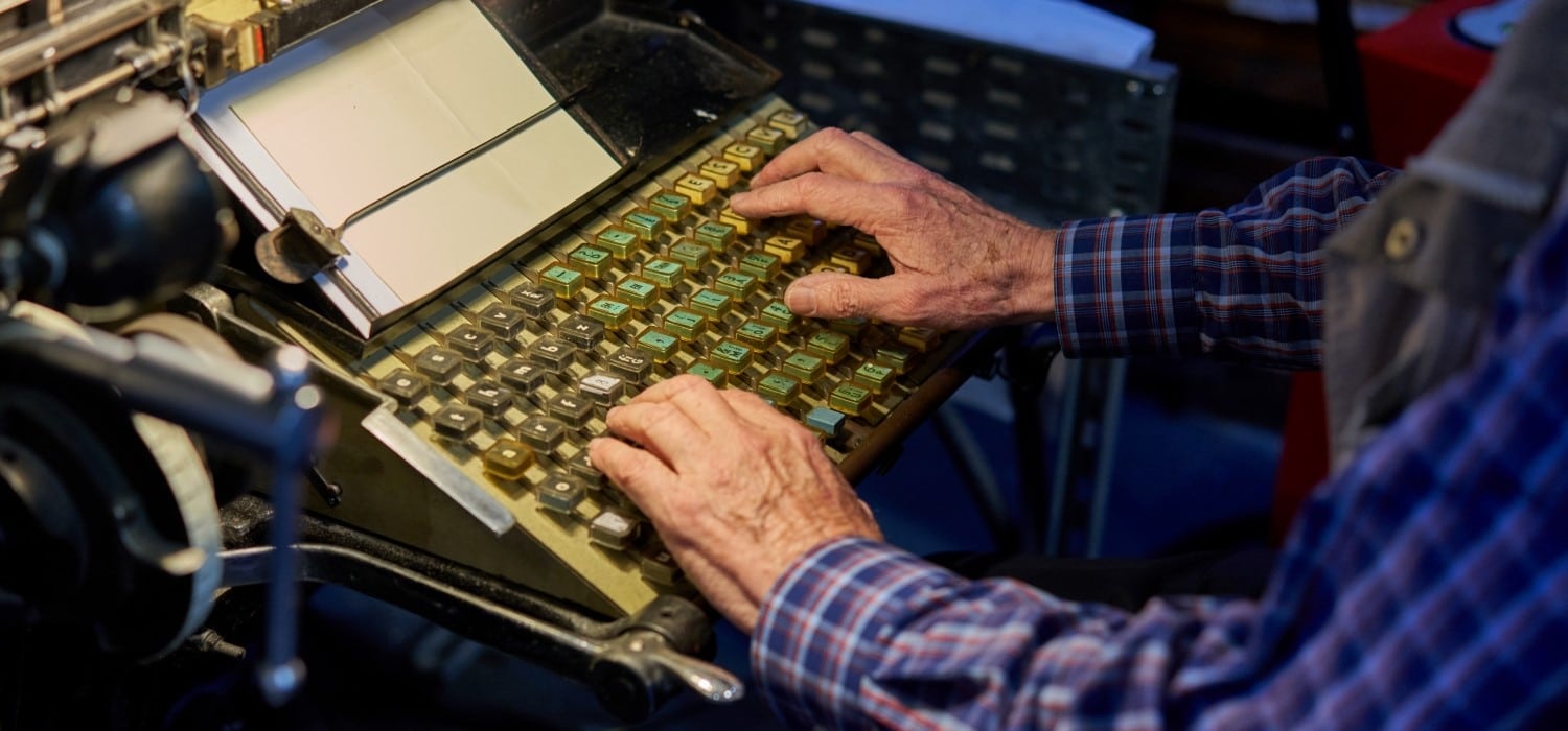 A linotype operator types on the keyboard of the machine