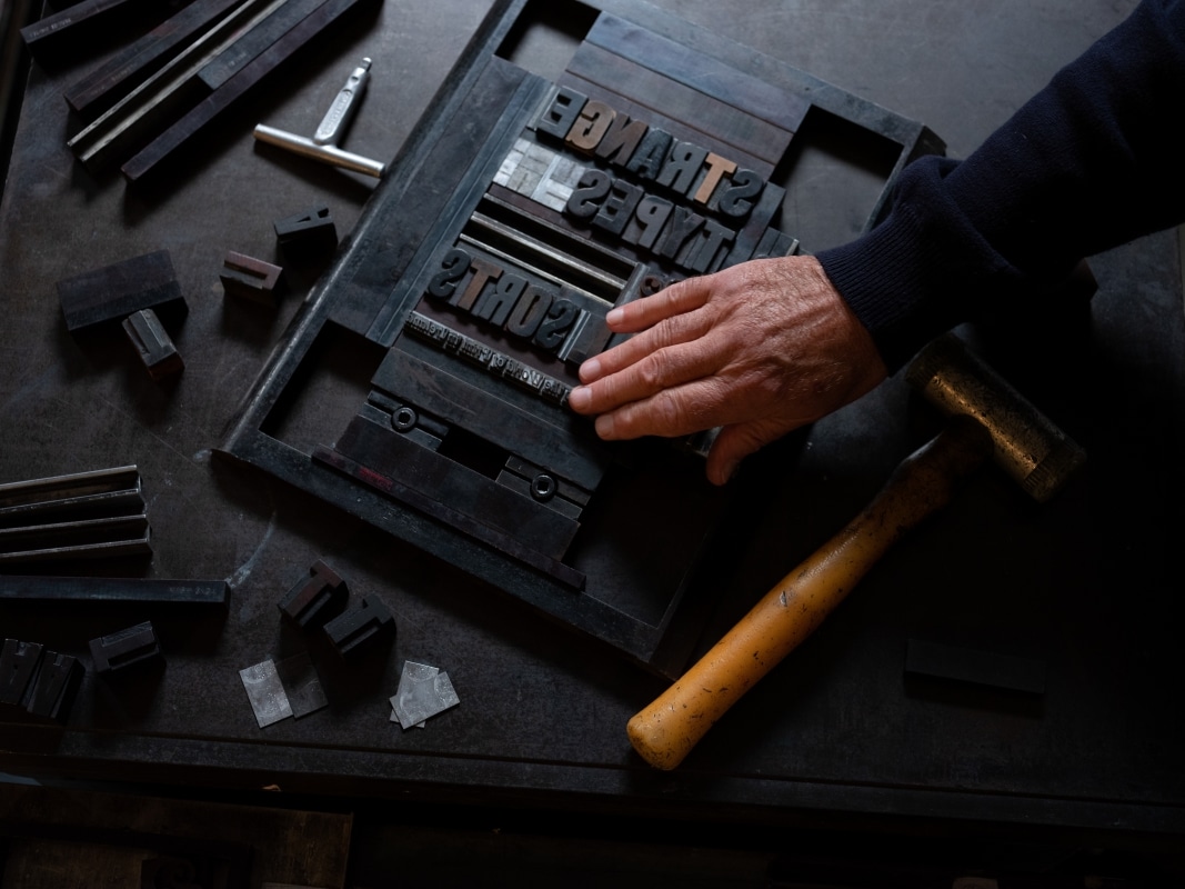 A compositor works on a setting with the text 'Strange Types & Odd Sorts'