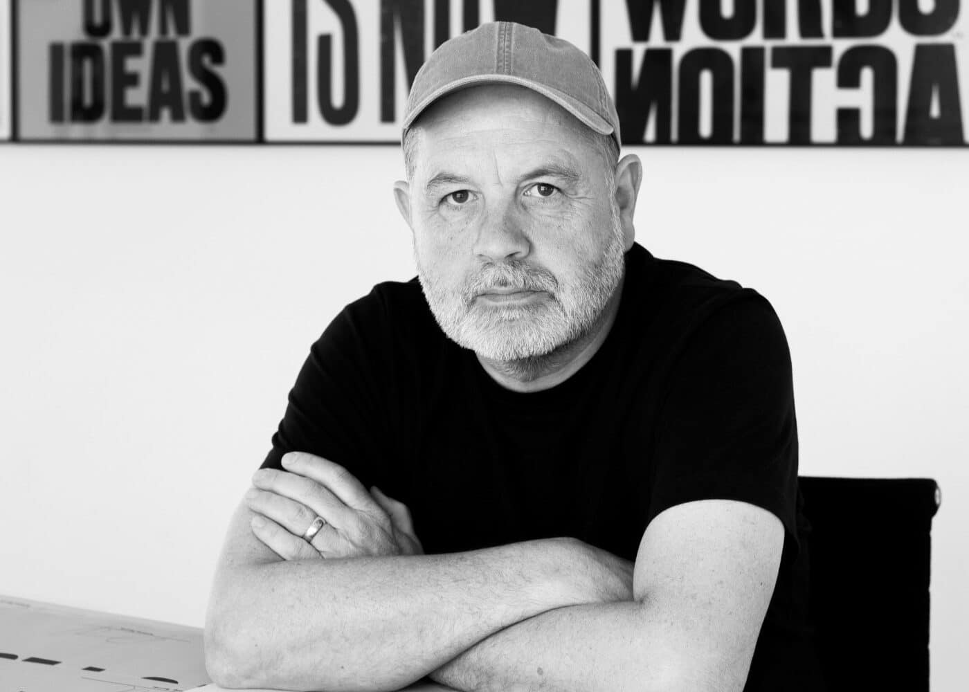 A photo of artist Anthony Burrill surrounded by some of his works