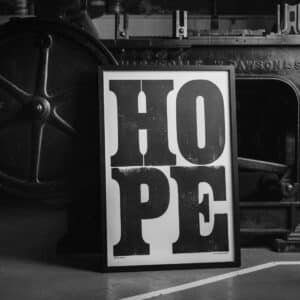 A framed version of Anthony Burrill's HOPE print, propped up against the Wharfdale Stop Cylinder Press on which it was printed