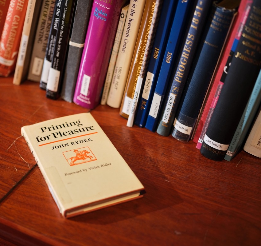 The book Printing for Pleasure resting on a shelf, with other books lined up behind it