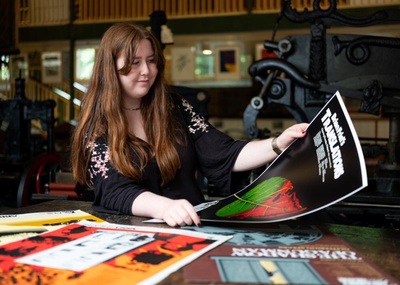 Intern Niamh examines a poster for Translations, illustrated with a green and red leaf