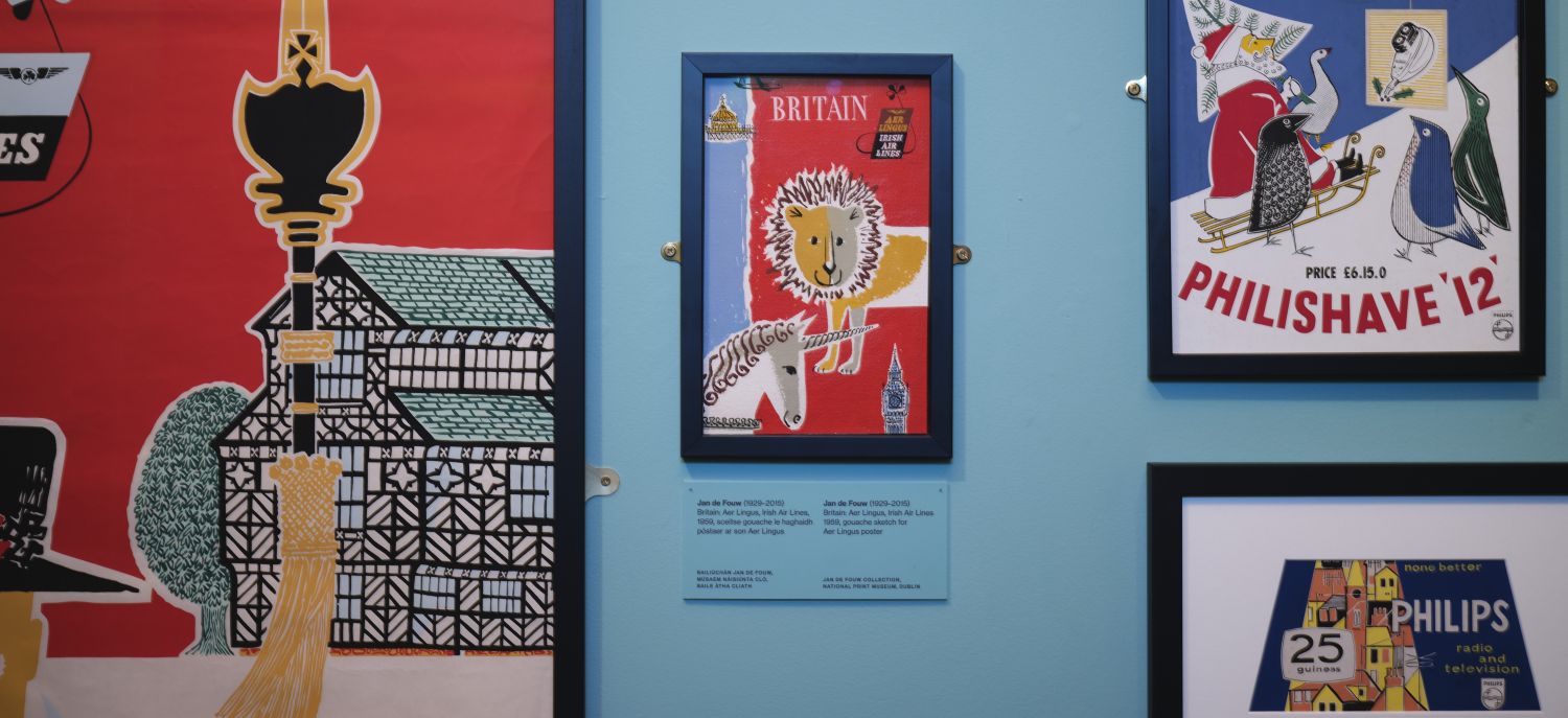 Various poster advertising travel and products hanging on a pale blue wall.