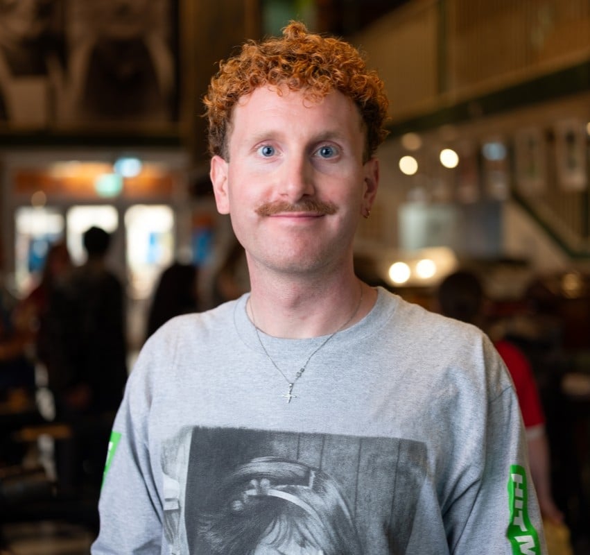 A man with re dhair and a moustache looks straight at the camera in a printing museum.