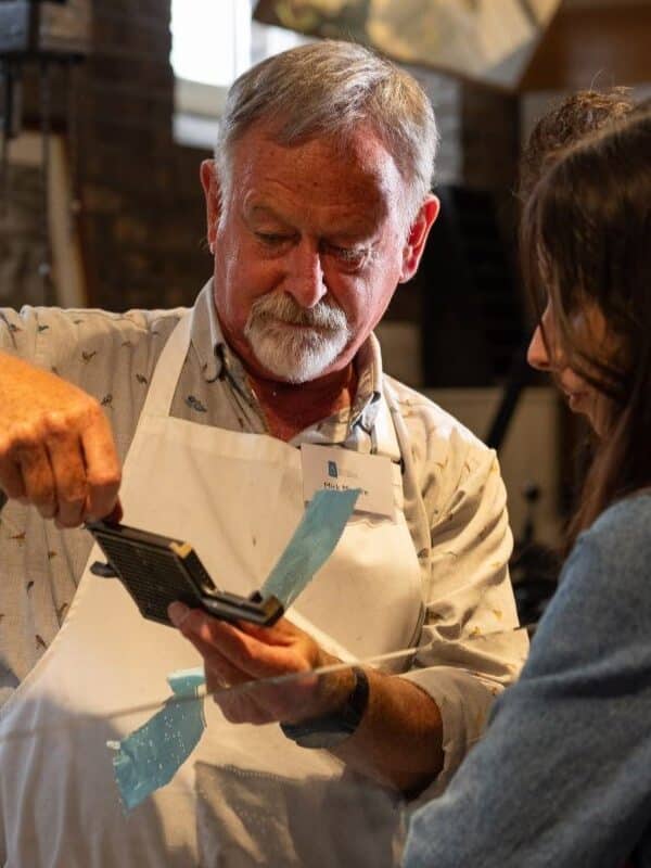 A man shows a piece of equipment to a young woman.