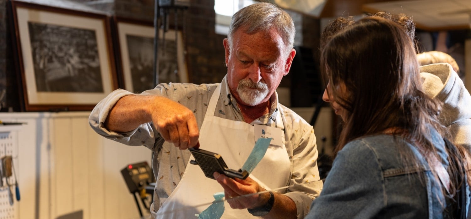 A man shows a piece of equipment to a young woman.