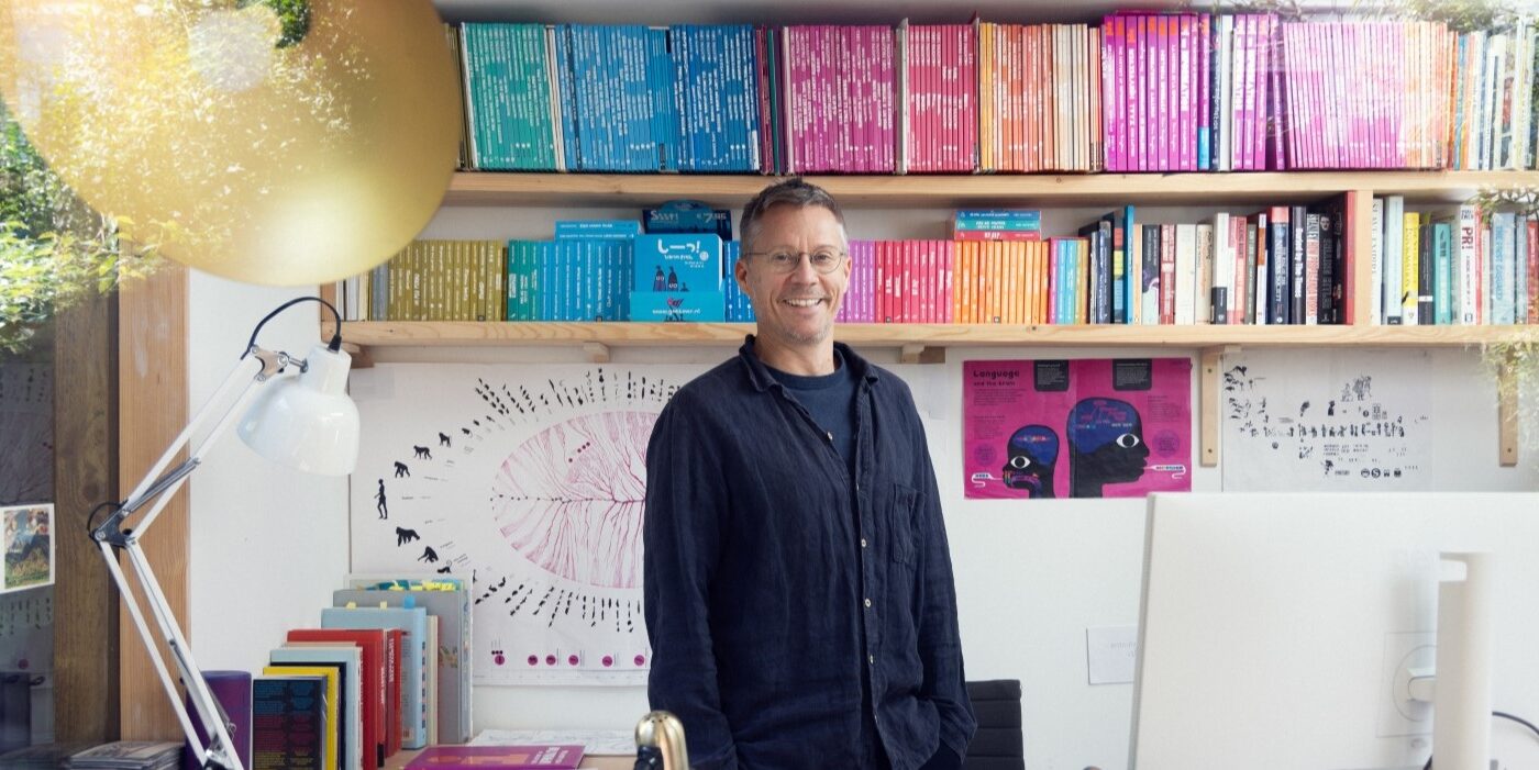 A photograph of author Chris Haughton standing in front of a shelf of colourful books.