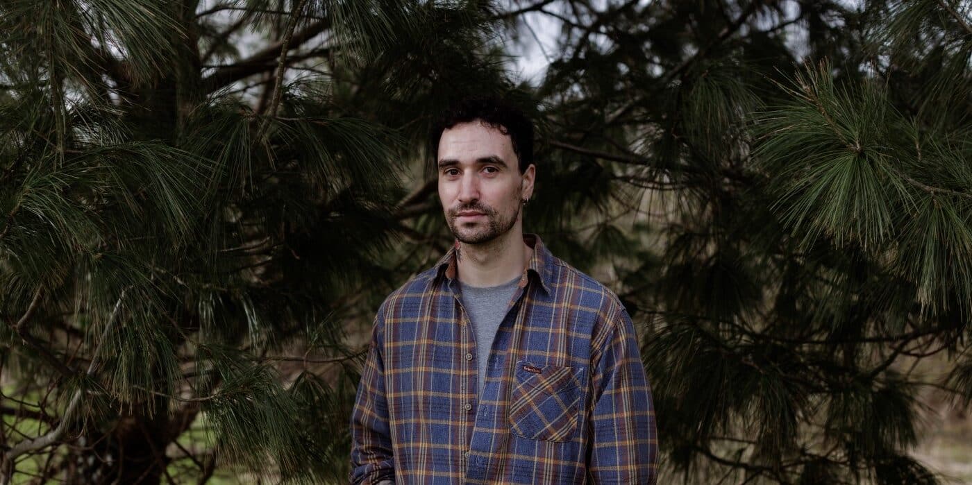 A photograph of author Djamel White standing in front of trees.