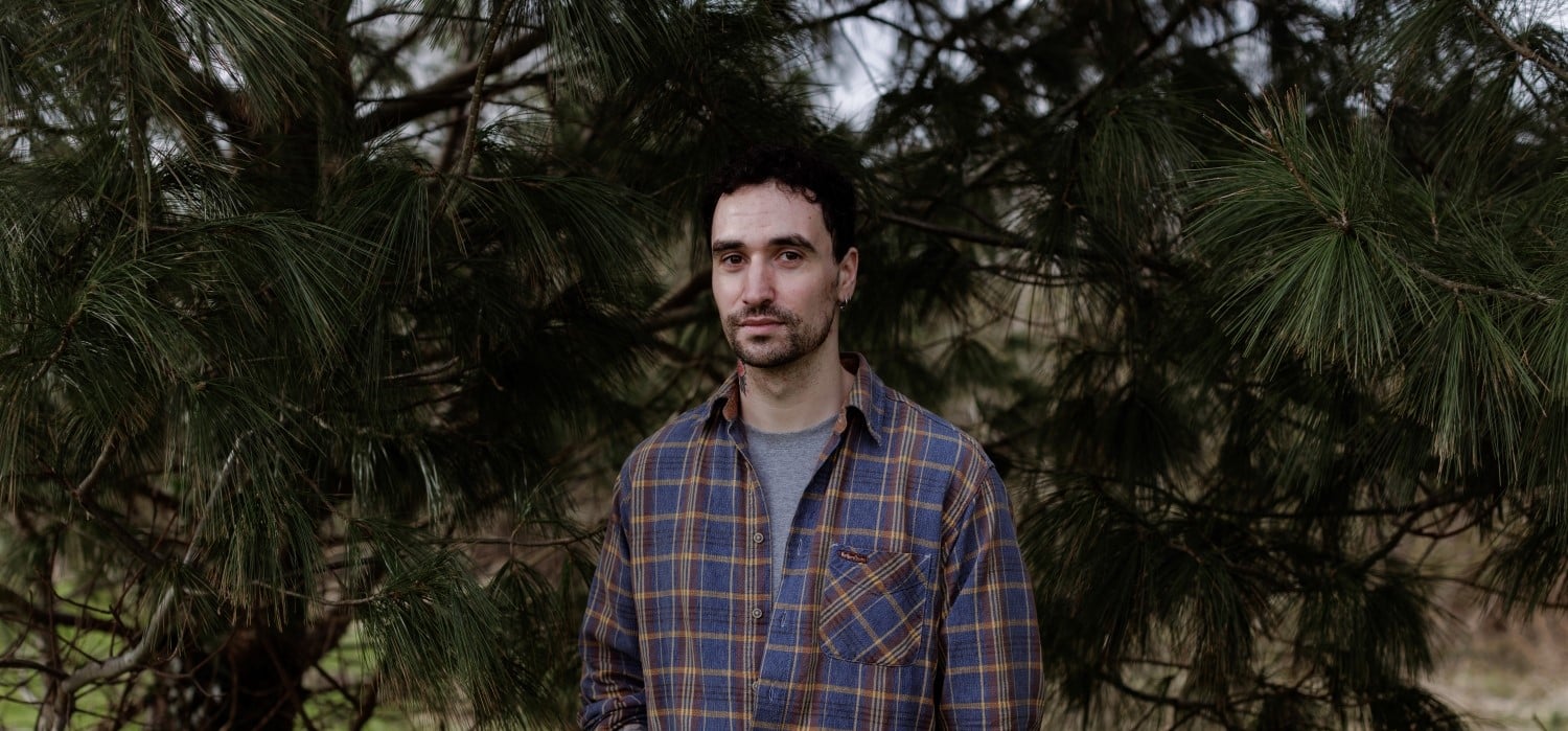 A photograph of author Djamel White standing in front of trees.