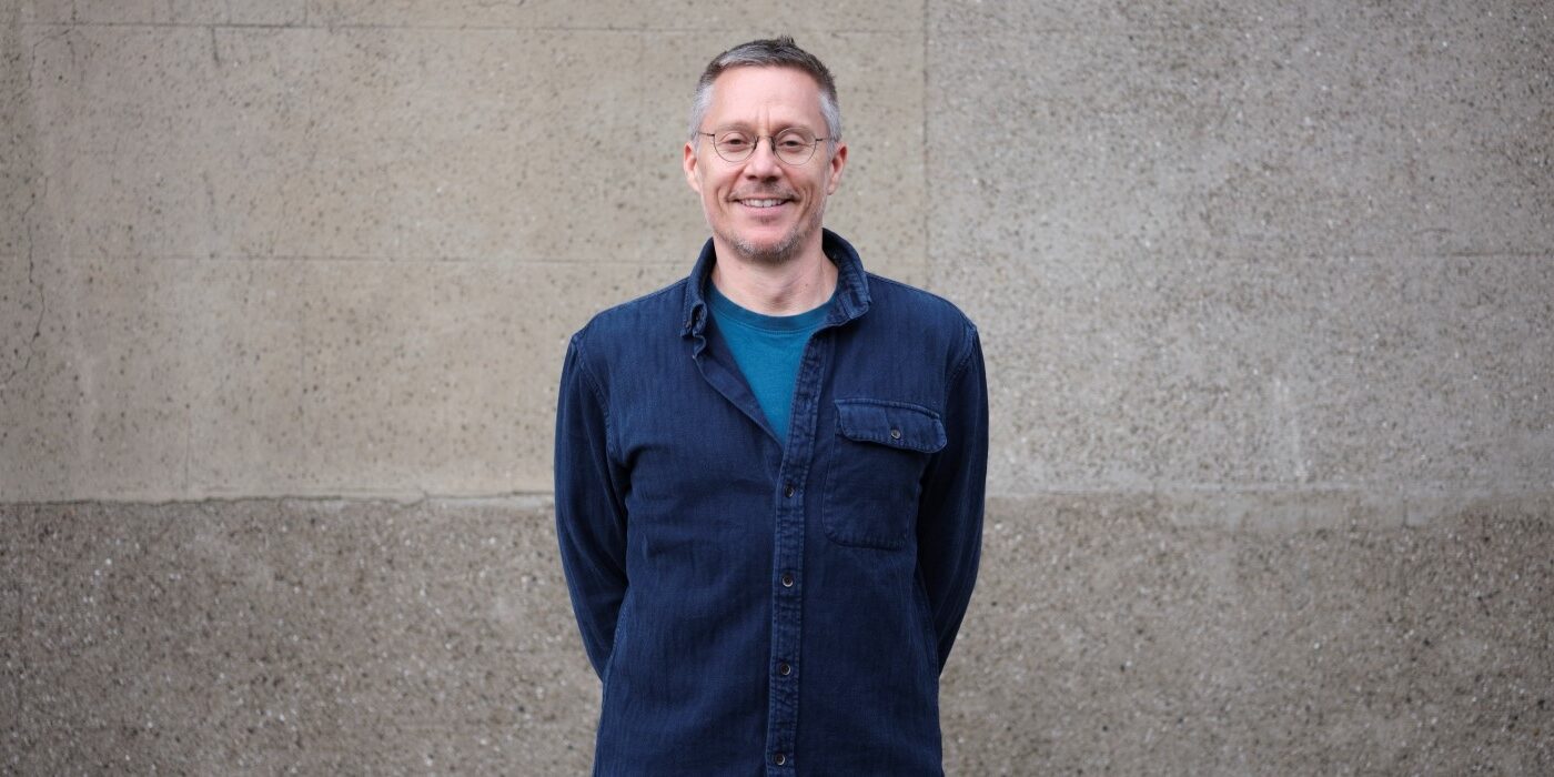 A photograph of author Chris Haughton standing in front of a stone wall background.
