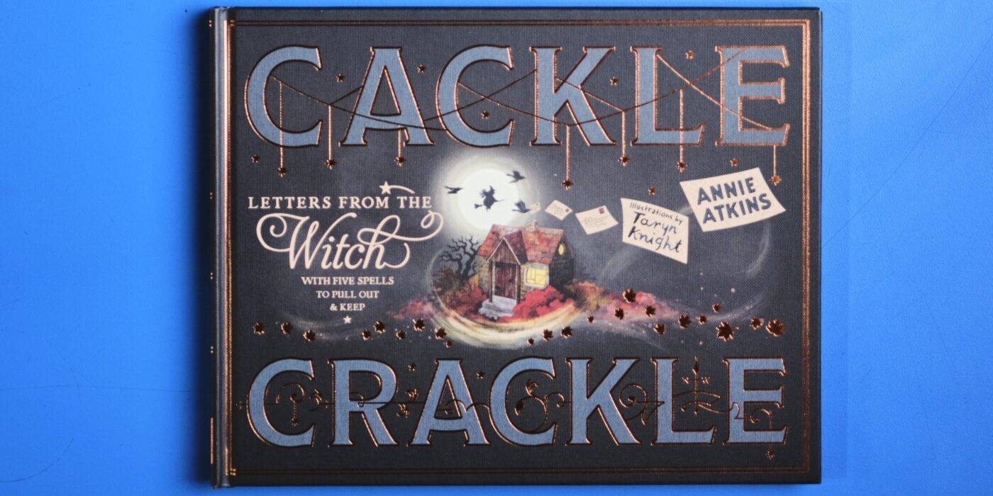 A photograph of the book Cackle Crackle on a blue background.