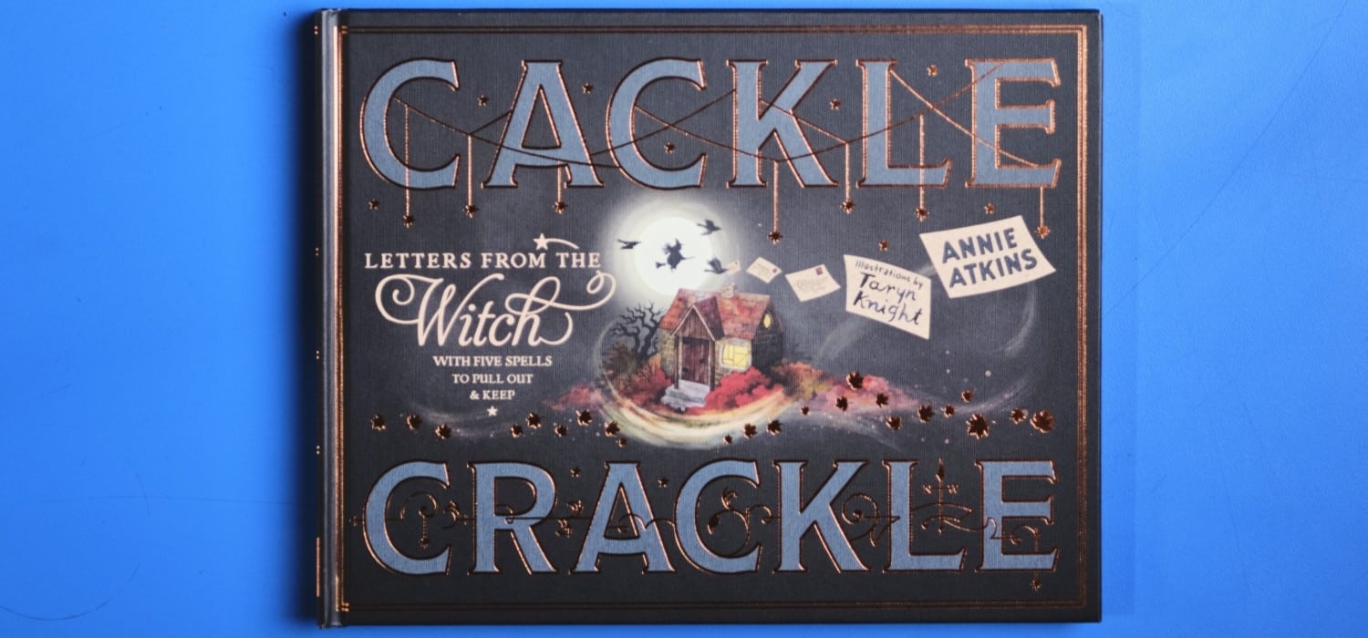 A photograph of the book Cackle Crackle on a blue background.