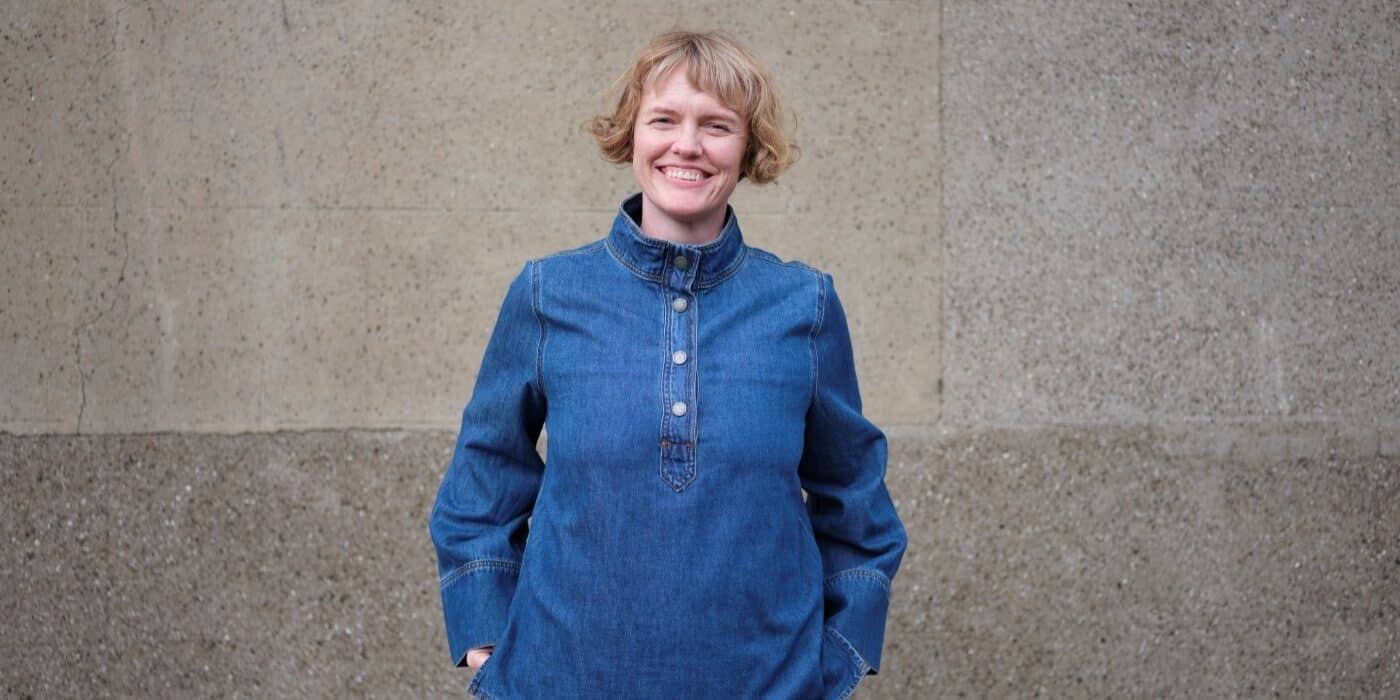 A photograph of Annie Atkins standing in front of a stone wall.