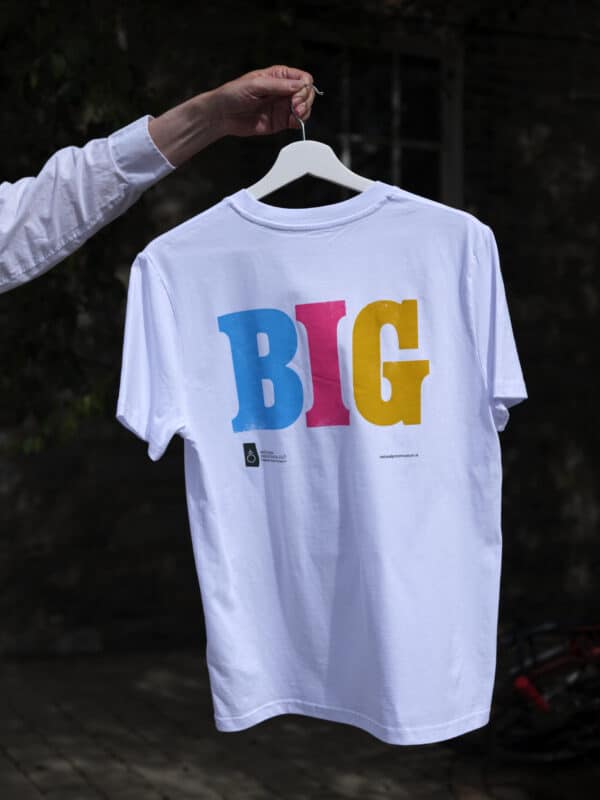 A t-shirt being held up by a man's arm on a hanger.