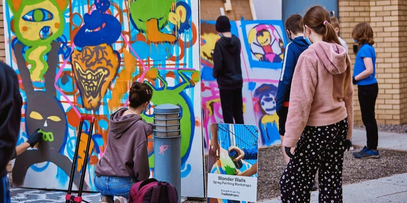 Young people working on a piece of graffiti art.