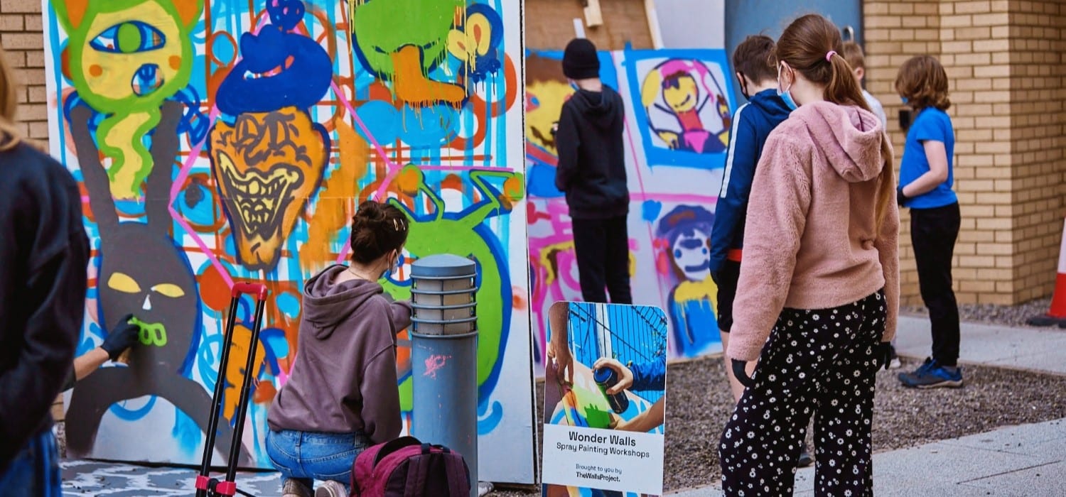 Young people working on a piece of graffiti art.