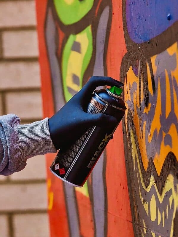 A hand spraying graffiti onto a wall.