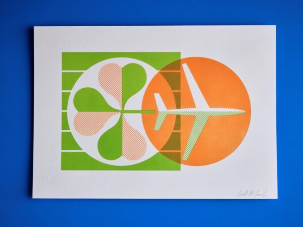 A letterpress print in orange and green of an airplane and a shamrock sits on top of a blue background.
