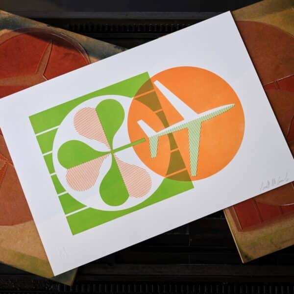 A letterpress print in orange and green of an airplane and a shamrock sits on top of printing plates.