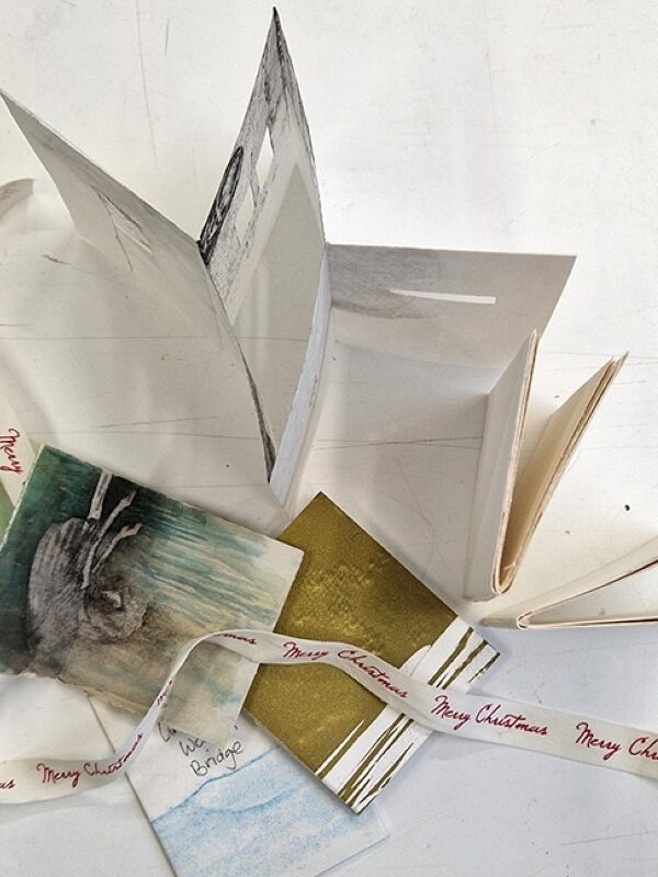 Pages and bookbinding materials sit in a pile.